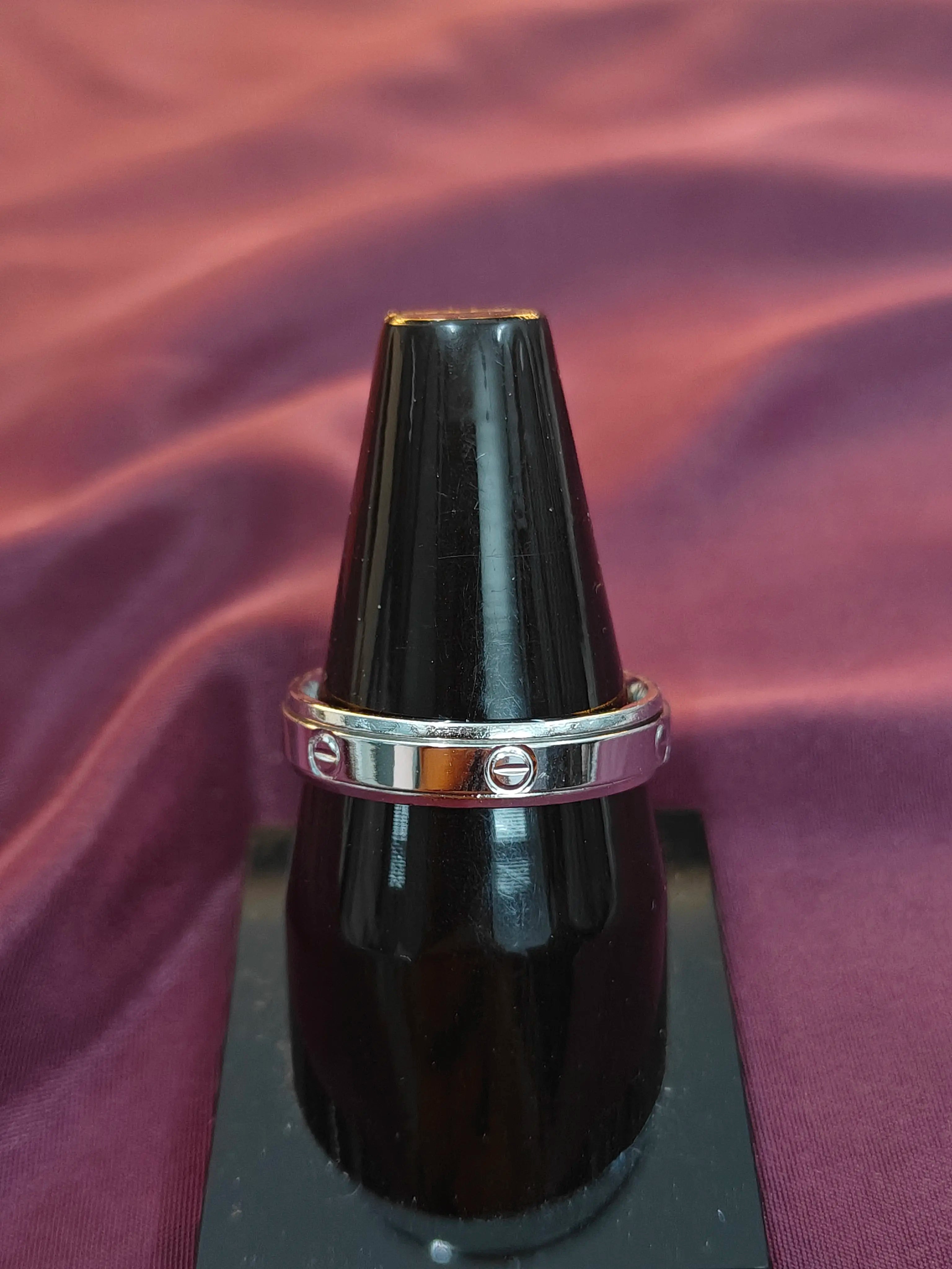 Black lacquer object with a silver ring on a purple fabric background